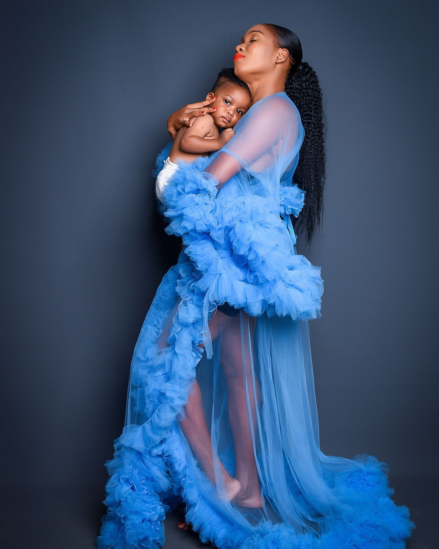 A woman in a blue dress is holding a baby.