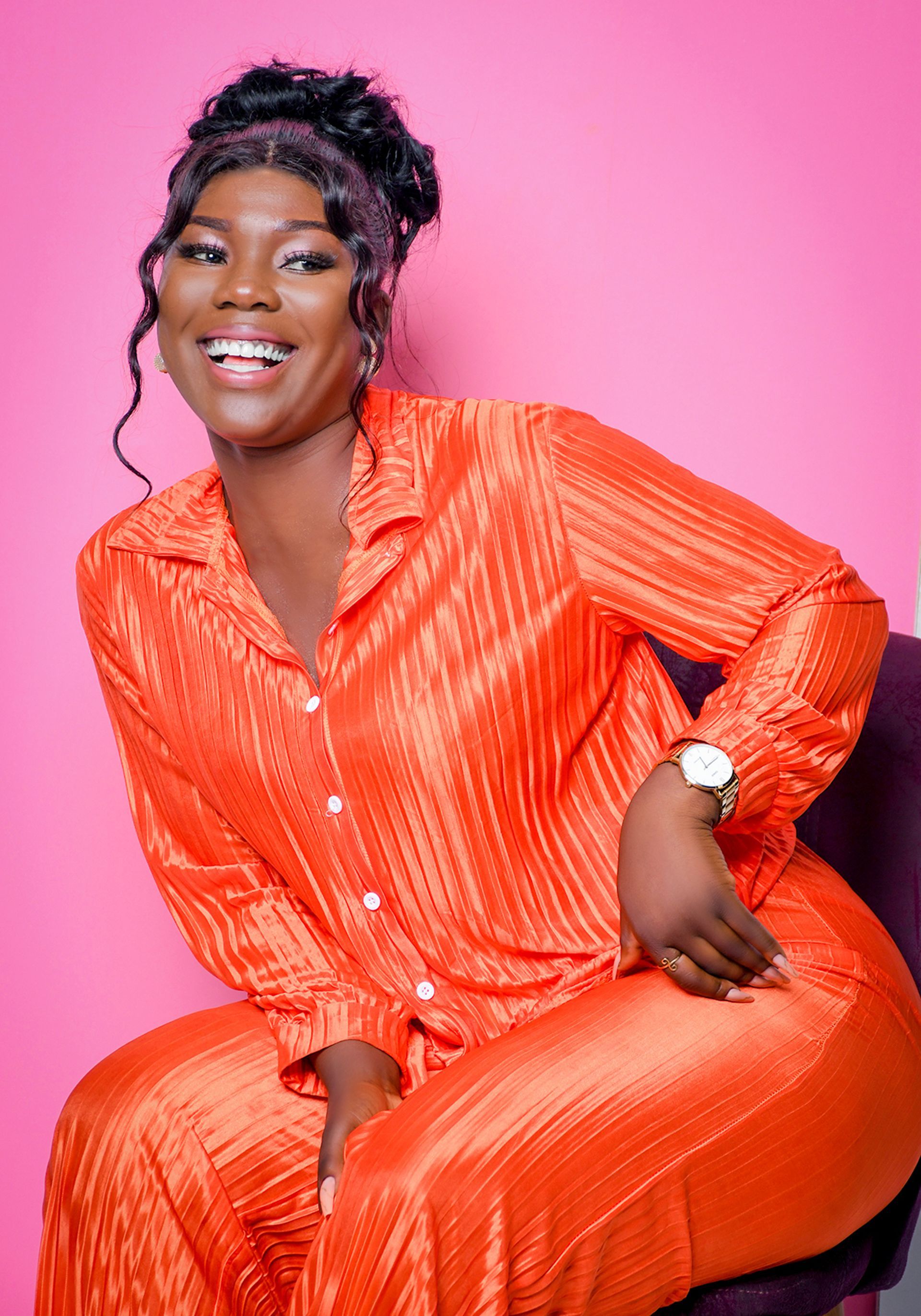 A woman in an orange shirt and pants is sitting in a chair.