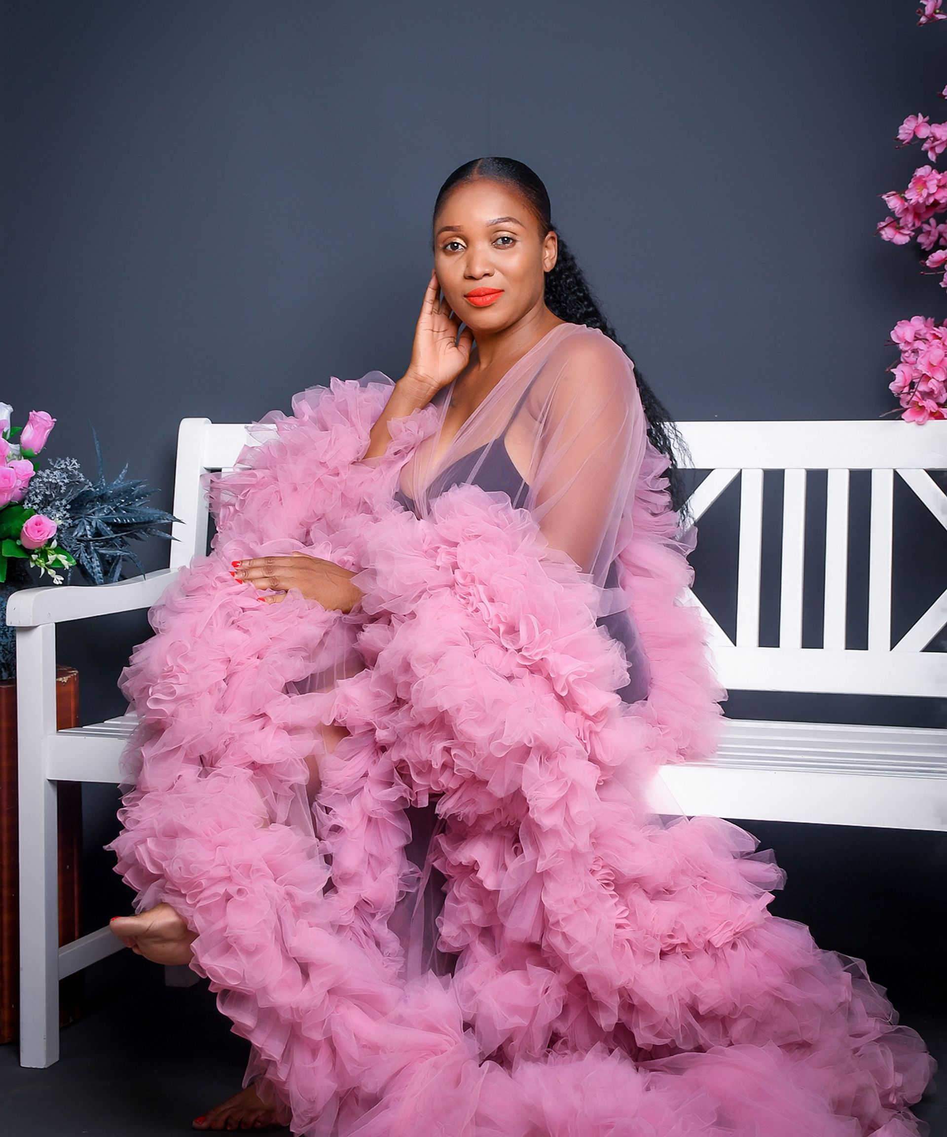 A woman in a pink dress is sitting on a bench.