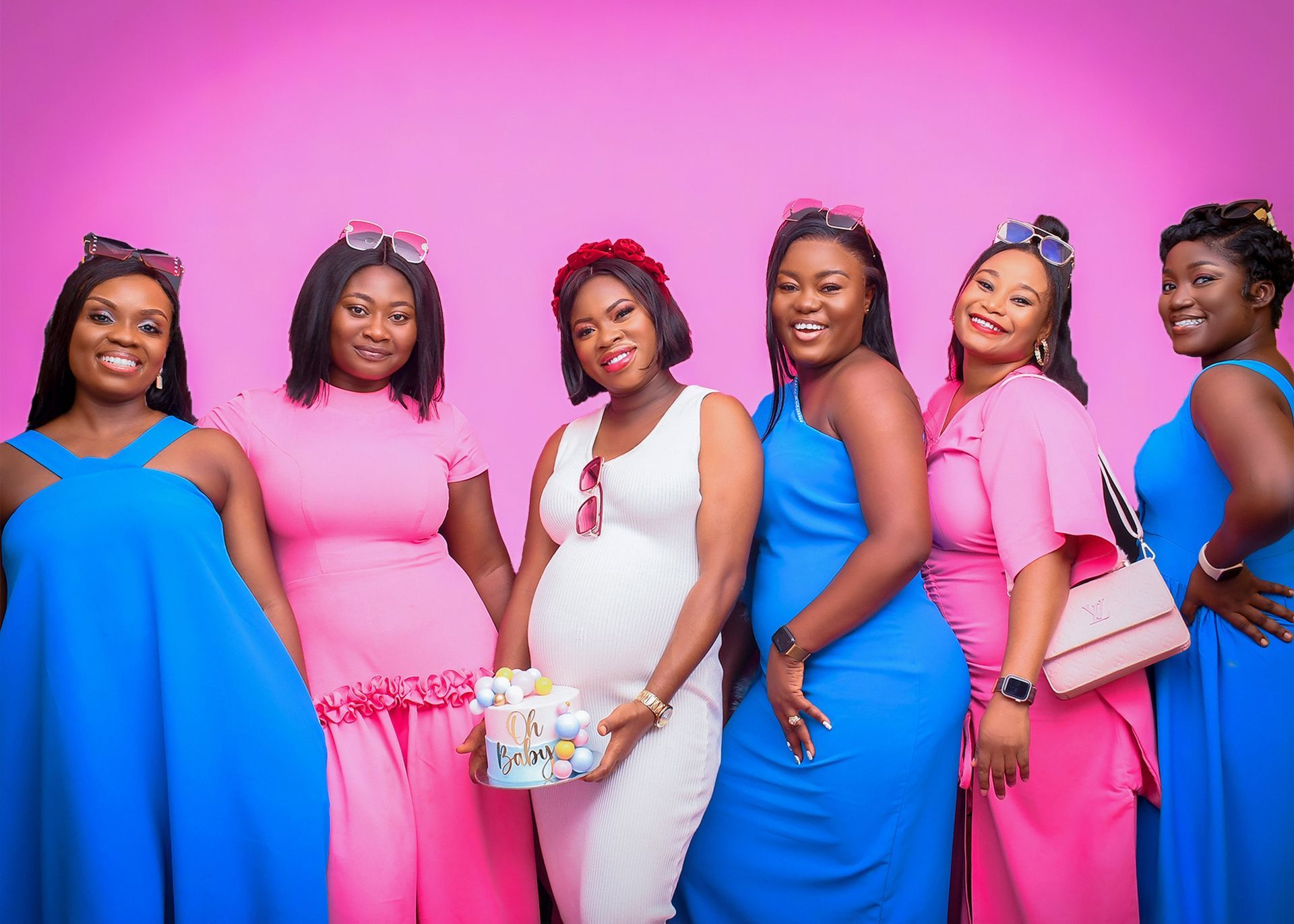 A group of women in pink and blue dresses are posing for a picture.