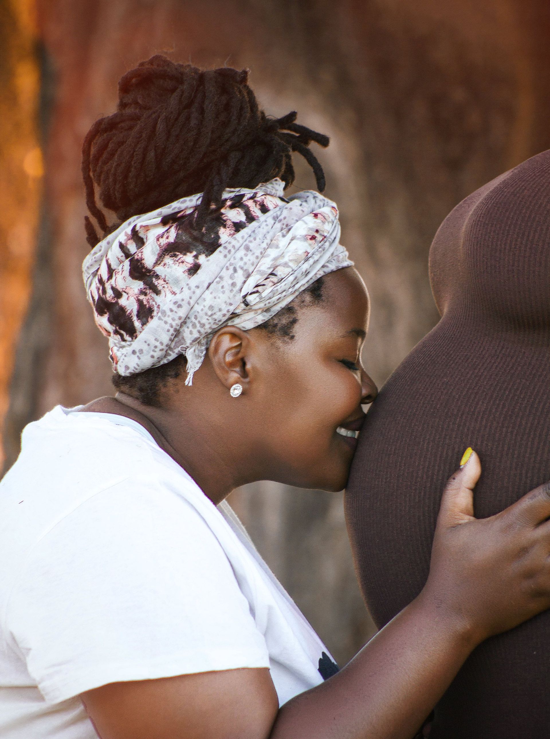 Woman kissing pregnant woman's belly