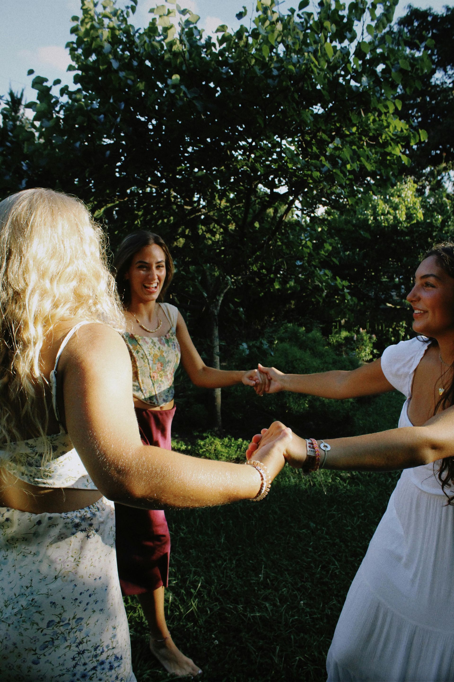 3 women holding hands smiling at each other and laughing