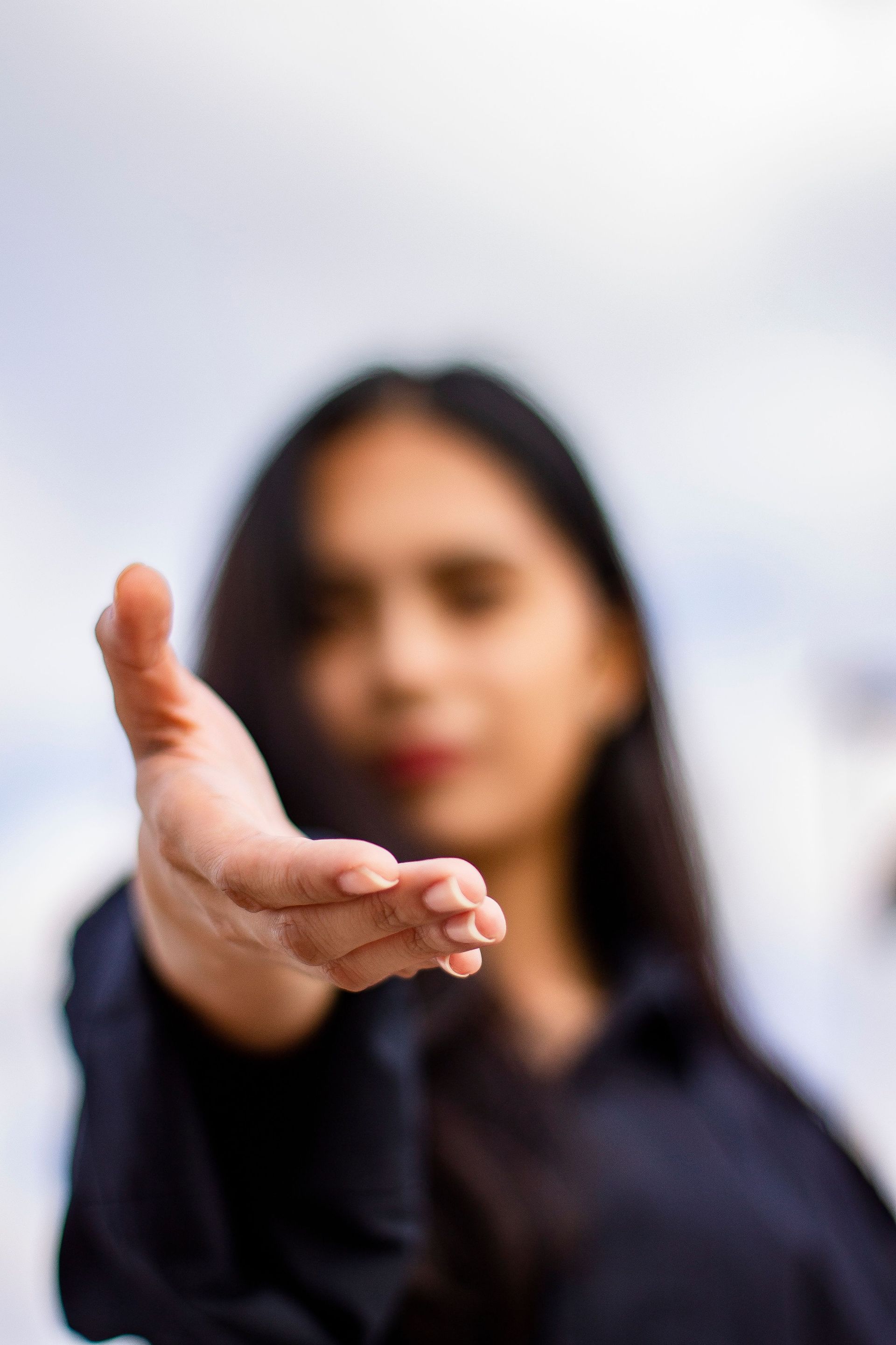 Woman extending hand to camera with invitation, blurry face