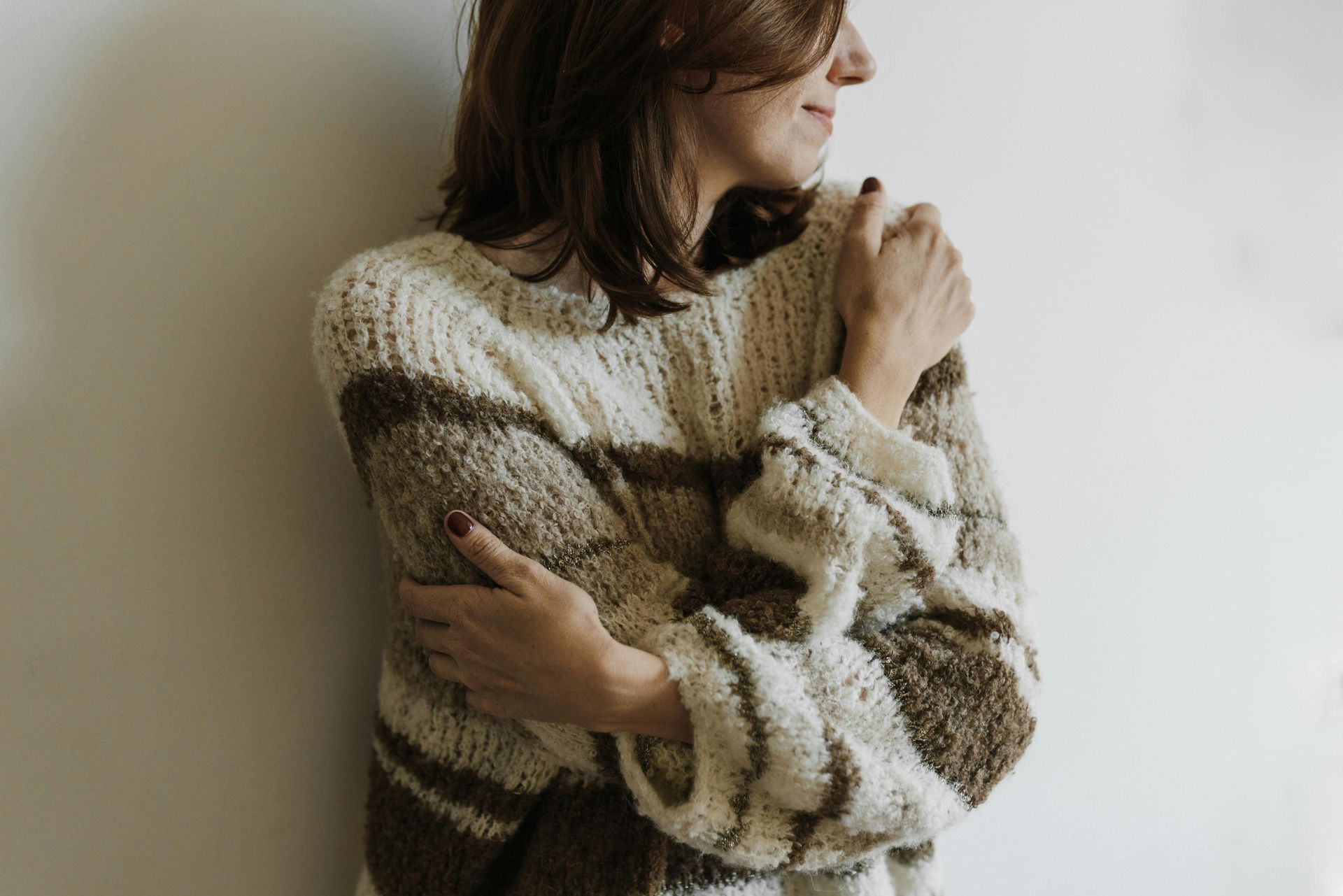 Woman in knitted sweater hugging herself 