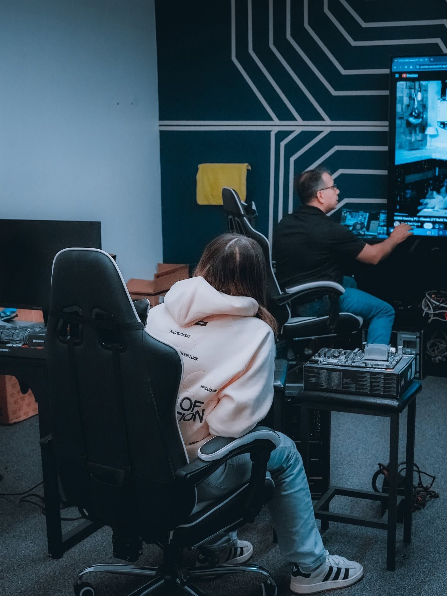 People seated at computers in a tech workspace with a dark circuit-pattern wall