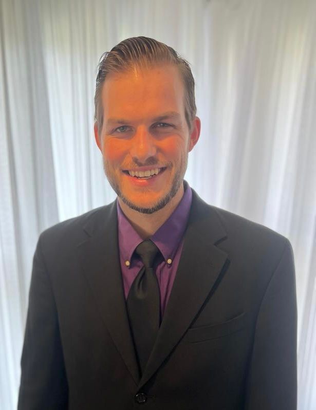 A man in a suit and tie is smiling for the camera.