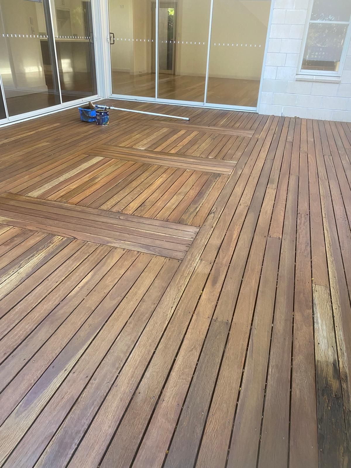 Wooden deck floor in an empty screened porch with glass doors and a small blue object near the wall. Job at Manly Vale