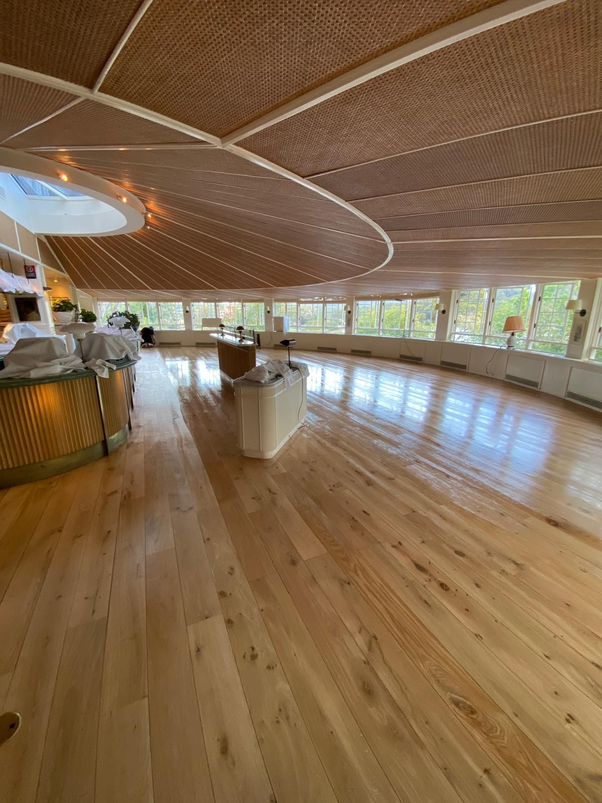 Spacious indoor lounge with a curved wooden ceiling, polished wood floor, and large windows overlooking greenery. At Newport arms, Newport