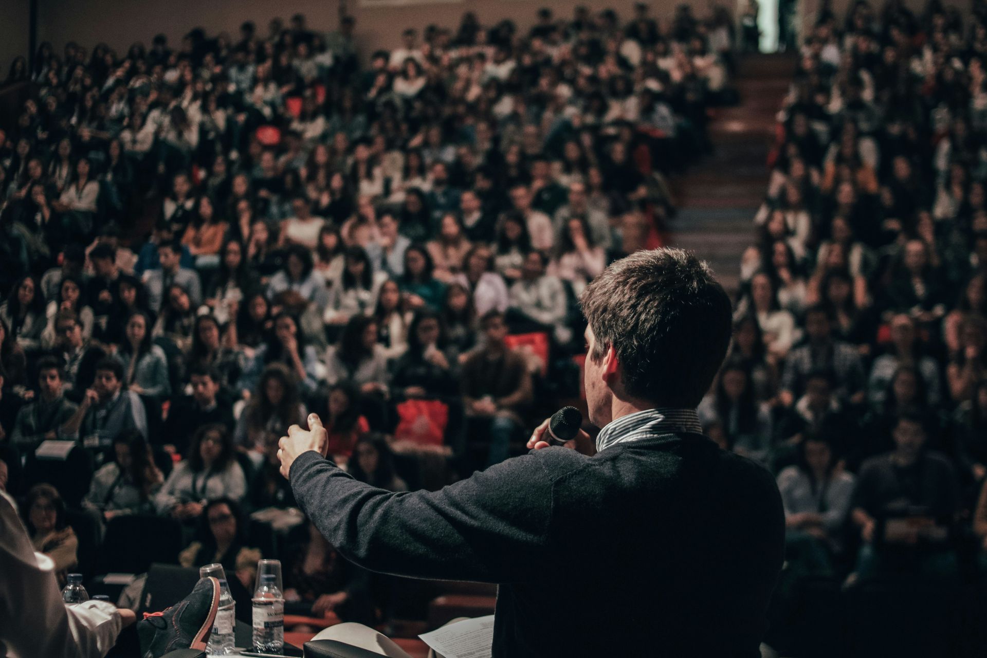 Un orateur s'adresse à un large public assis dans une salle de conférence