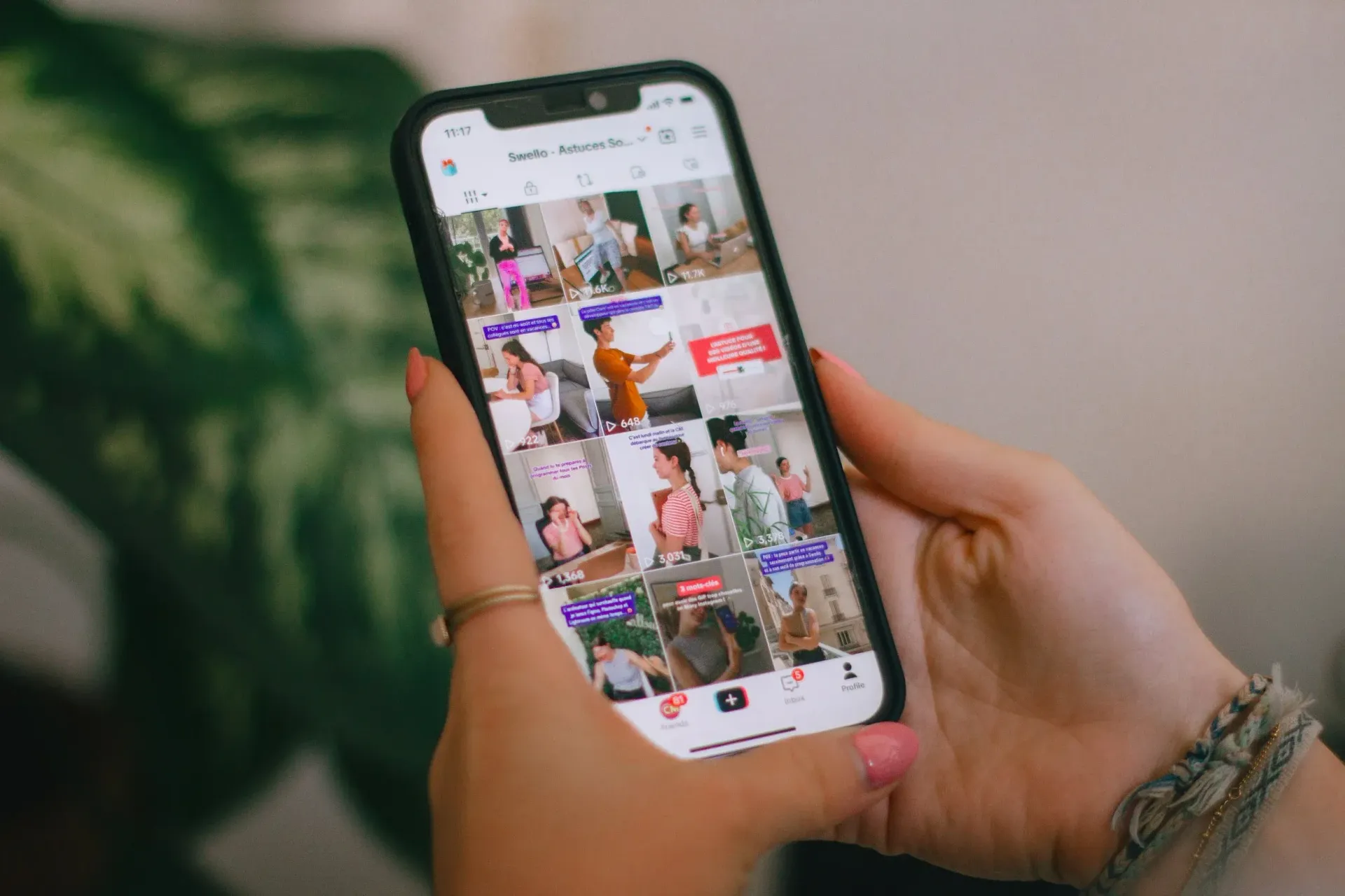 Des mains tenant un smartphone affichant le flux d'une application de partage de photos