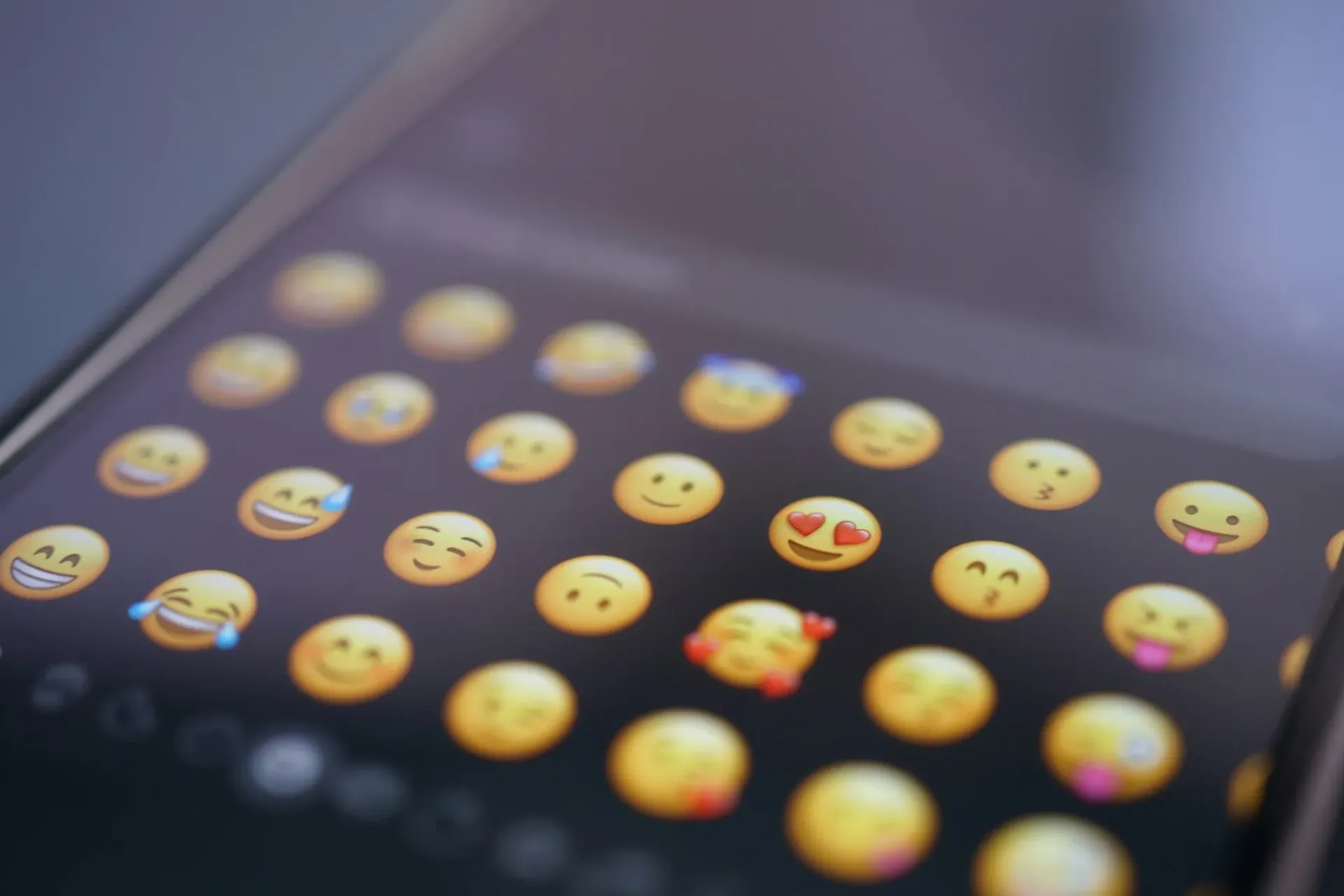 Écran de smartphone affichant une grille d'icônes emoji colorées sur fond sombre