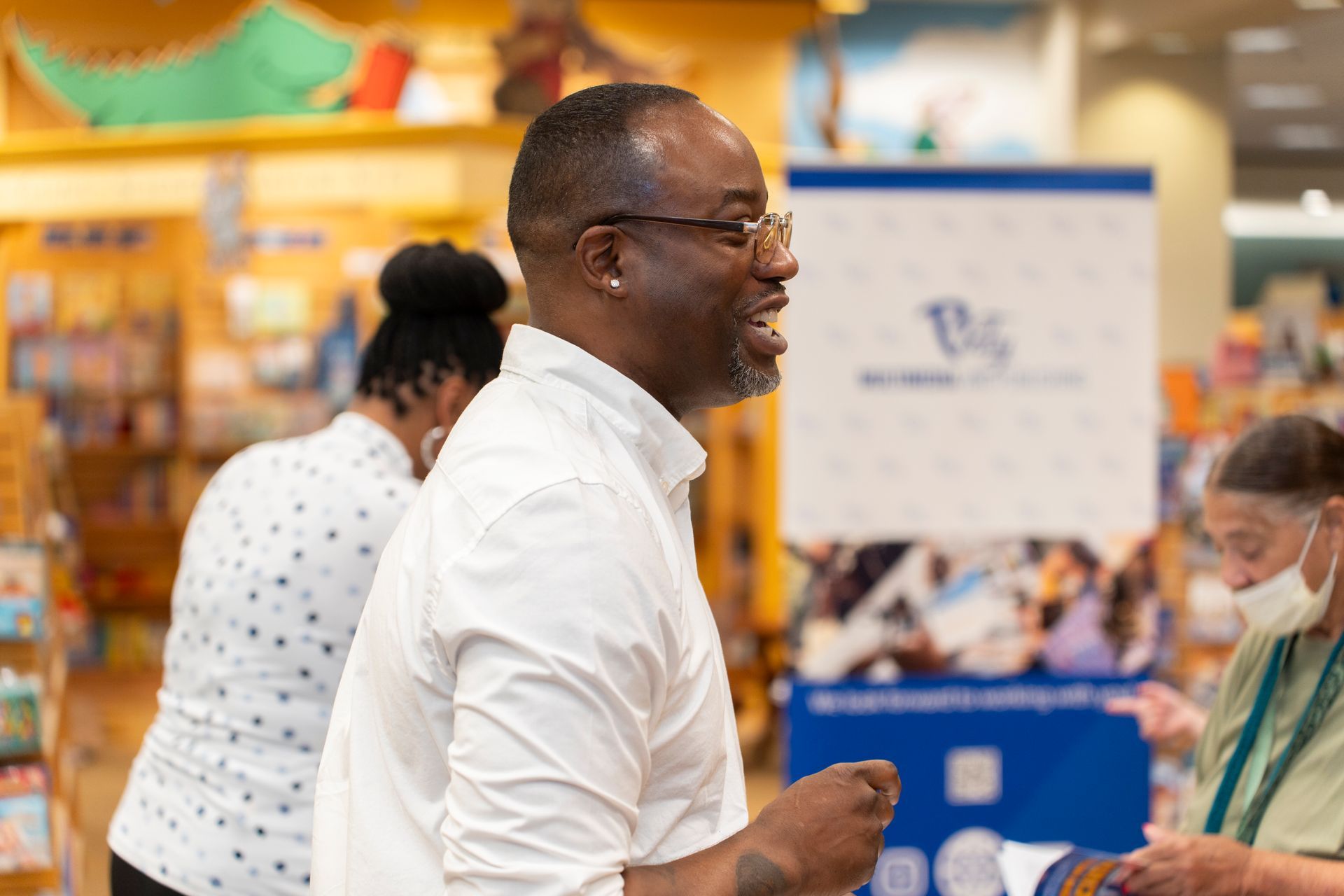 A man in a white shirt is talking to a woman in a bookstore.