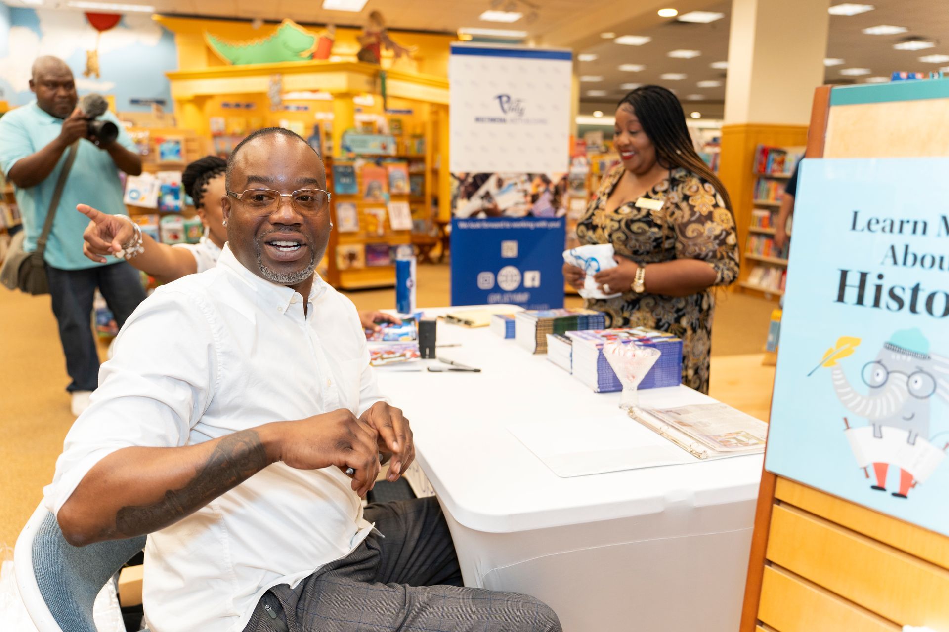 A man is sitting at a table in a bookstore.