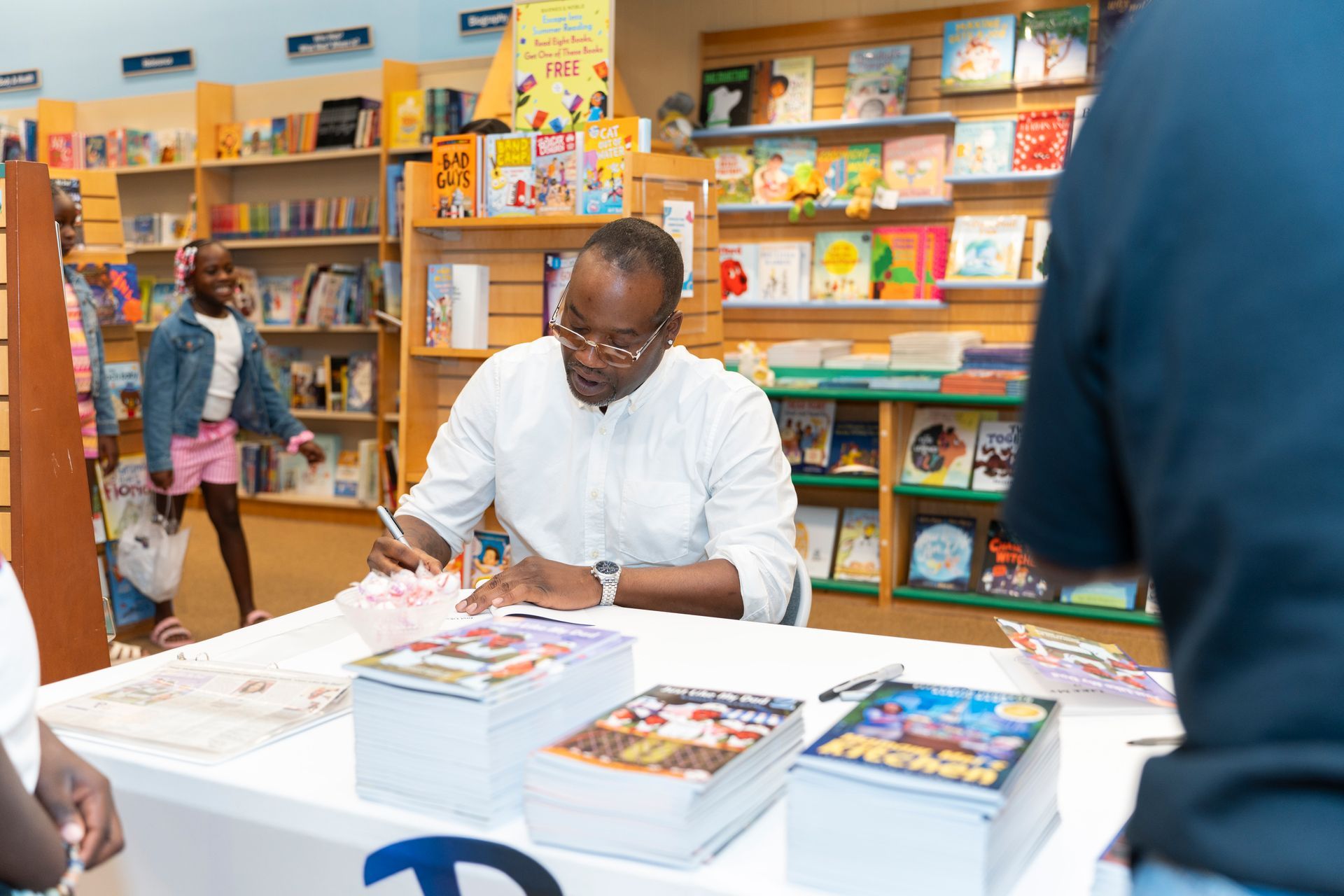 A man and a woman are sitting at a table in a bookstore holding books.