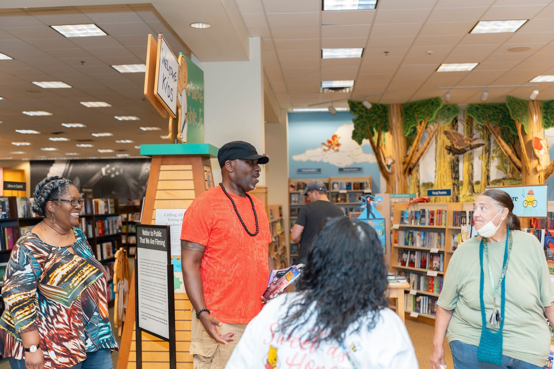 A group of people are standing in a library talking to each other.