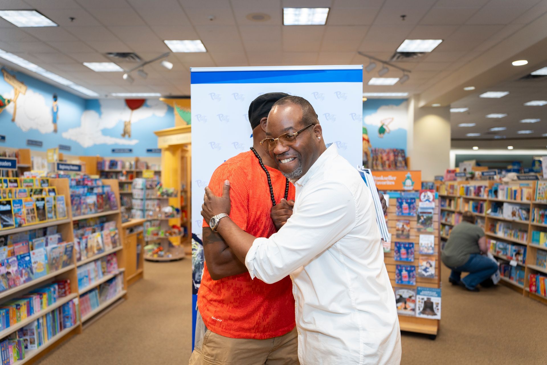 Two men are hugging each other in a bookstore.