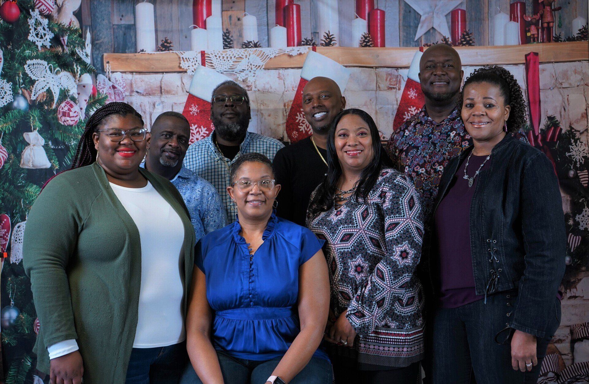A group of people are posing for a picture in front of a christmas tree.