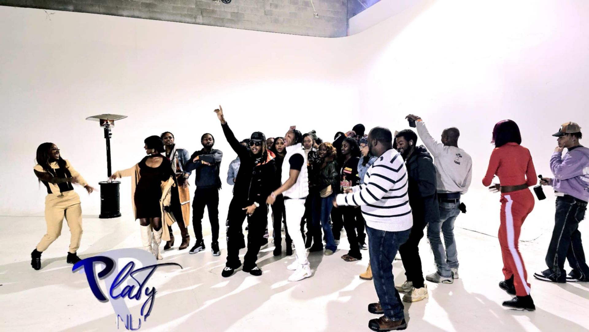 A group of people are dancing in a white room.