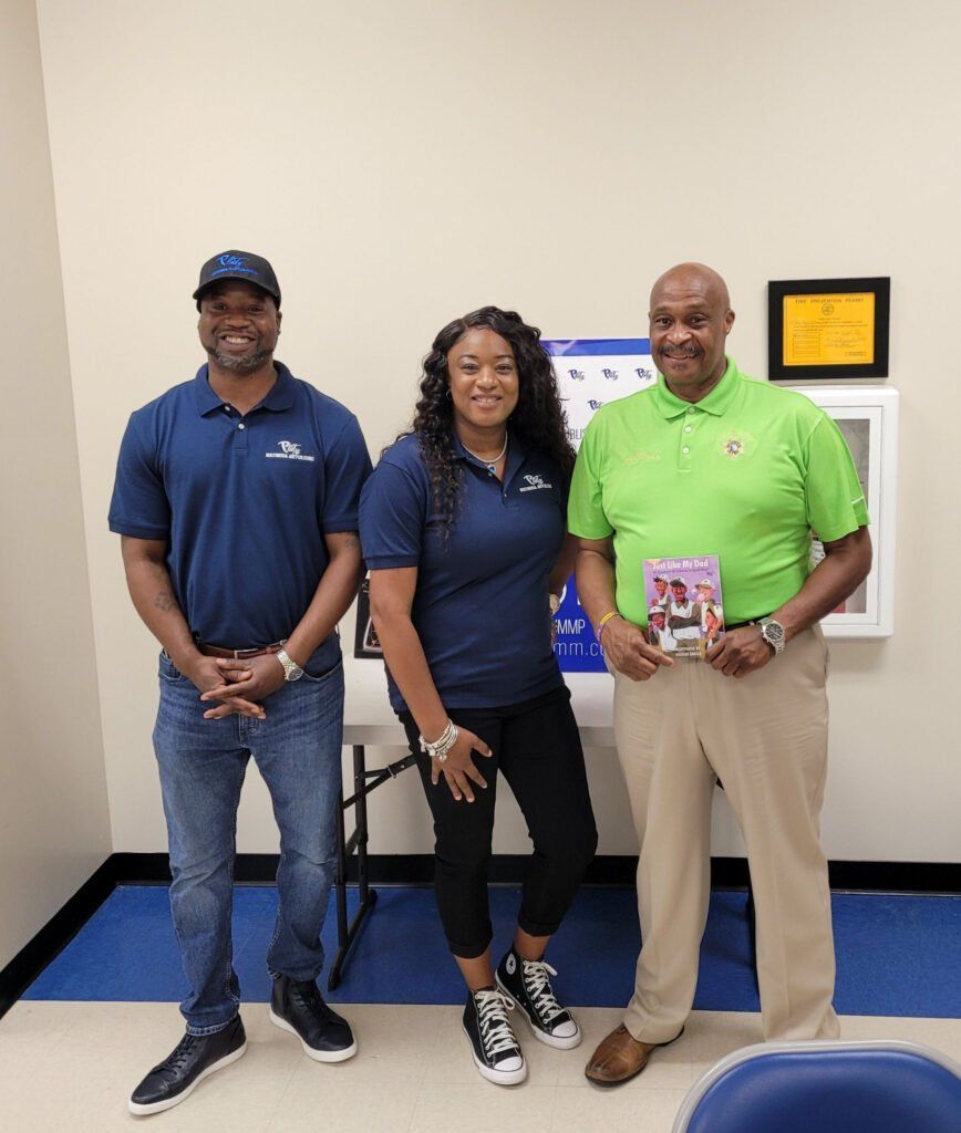 Three people are standing next to each other in a room.