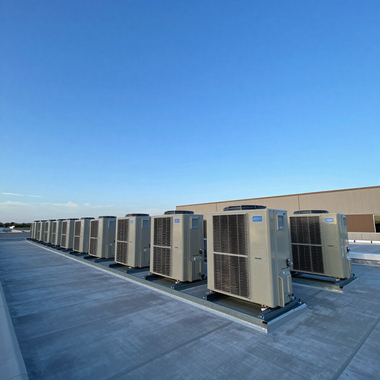 Row of rooftop HVAC units on a blue industrial roof under a clear sky