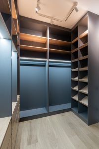 A walk in closet with lots of shelves and a wooden floor.