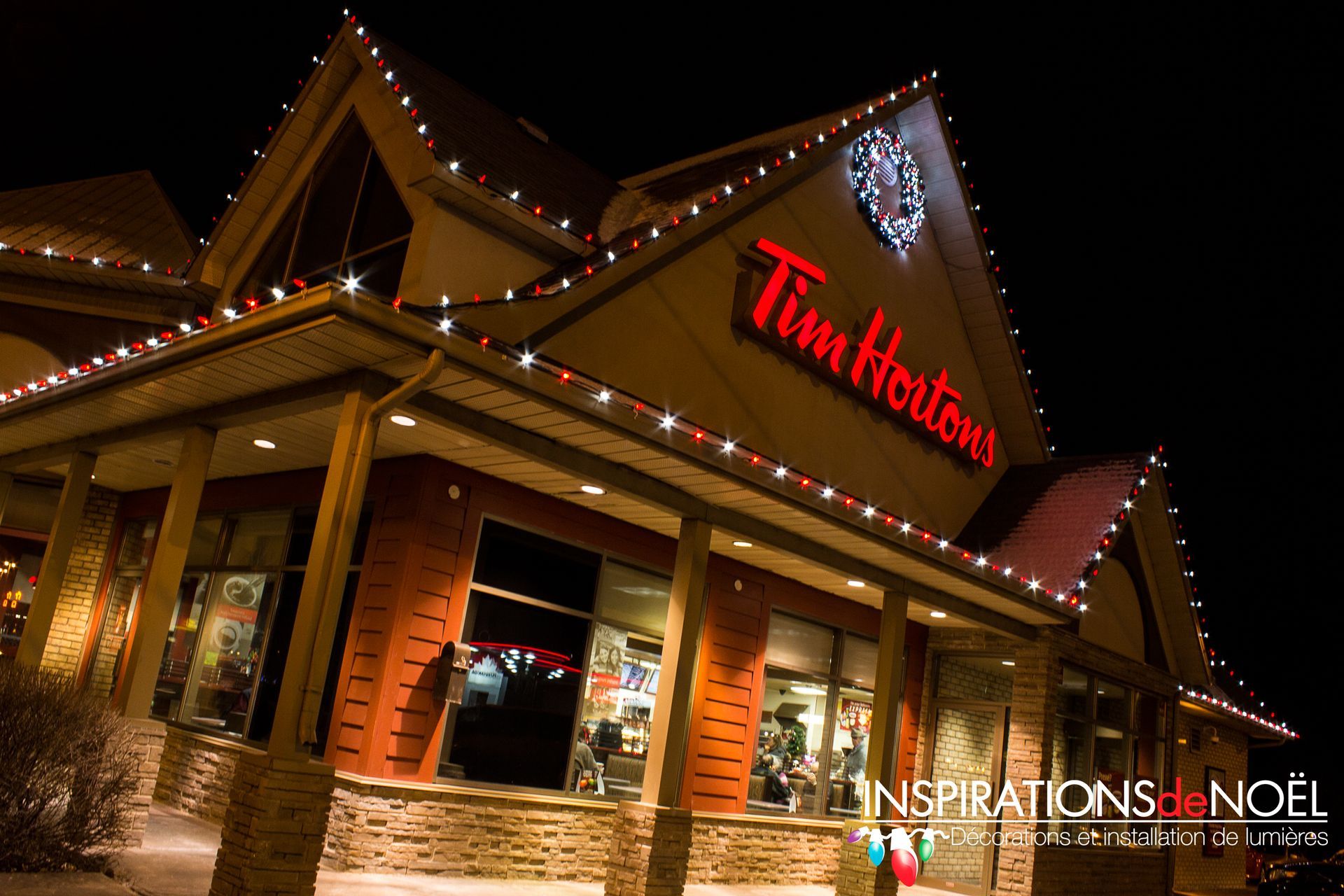 Tim Hortons at night with Christmas lights on the roof, exterior view.