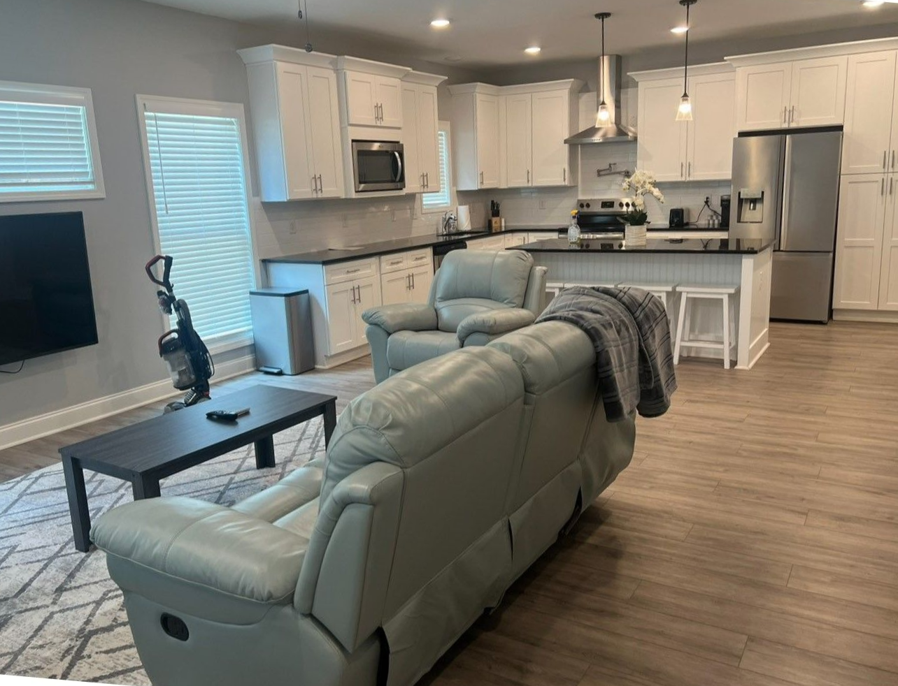 Modern open kitchen and living room with gray sofa, coffee table, and stainless steel appliances