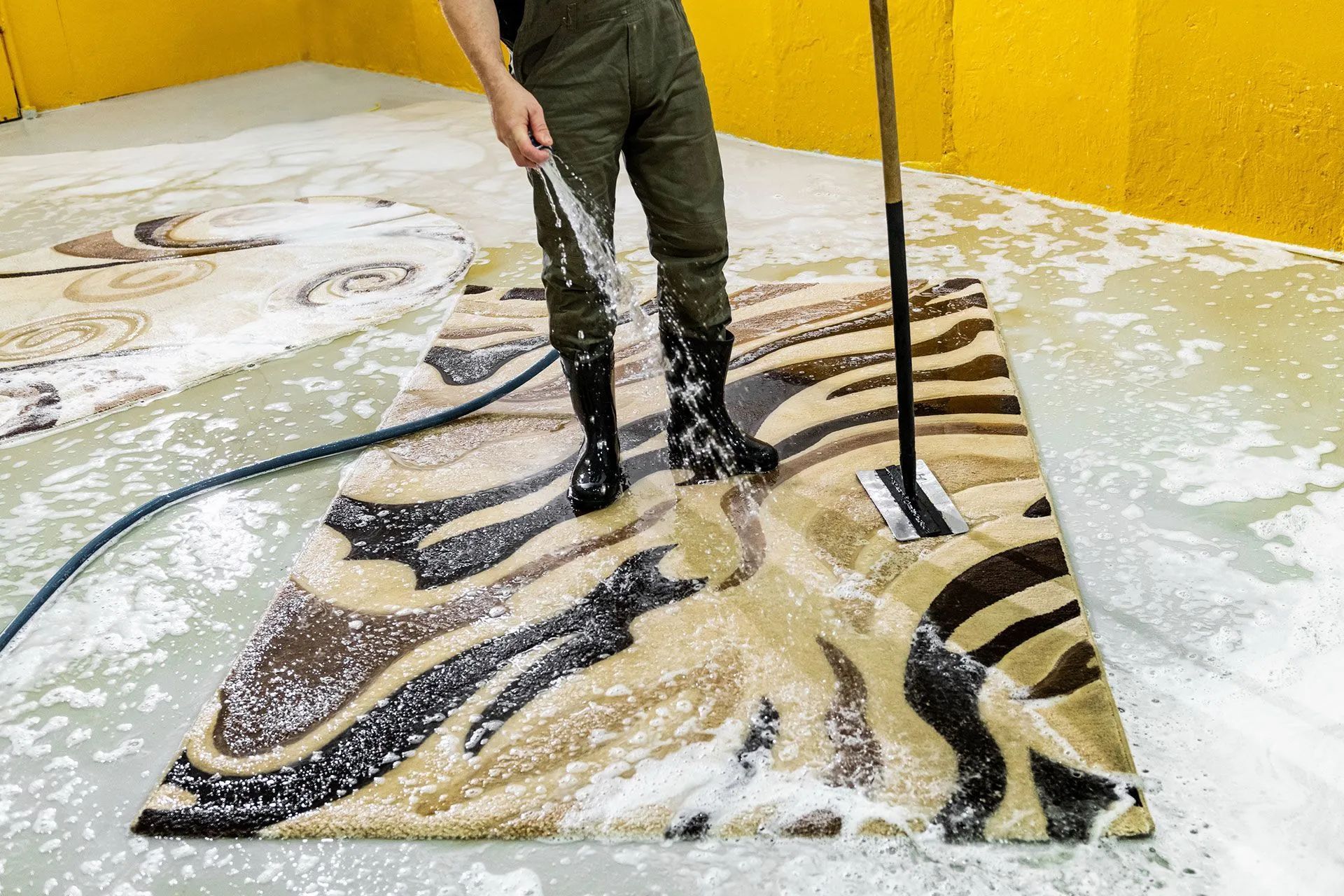 Person standing on a zebra-themed floor mural with water and soap suds, in a yellow room