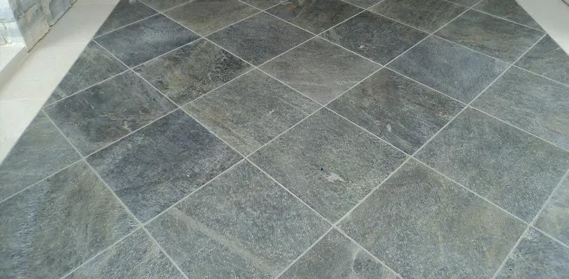 Gray stone tile floor with diagonal grout lines and a small white edge in the corner