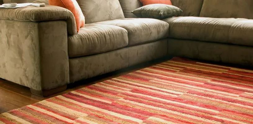 Sectional couch in a living room with a red striped rug on wooden floor