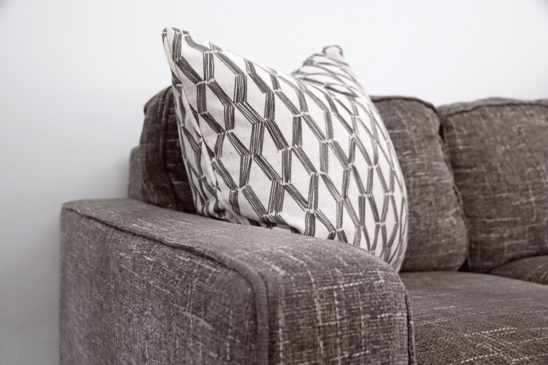 Patterned throw pillow on a brown couch armrest in a living room