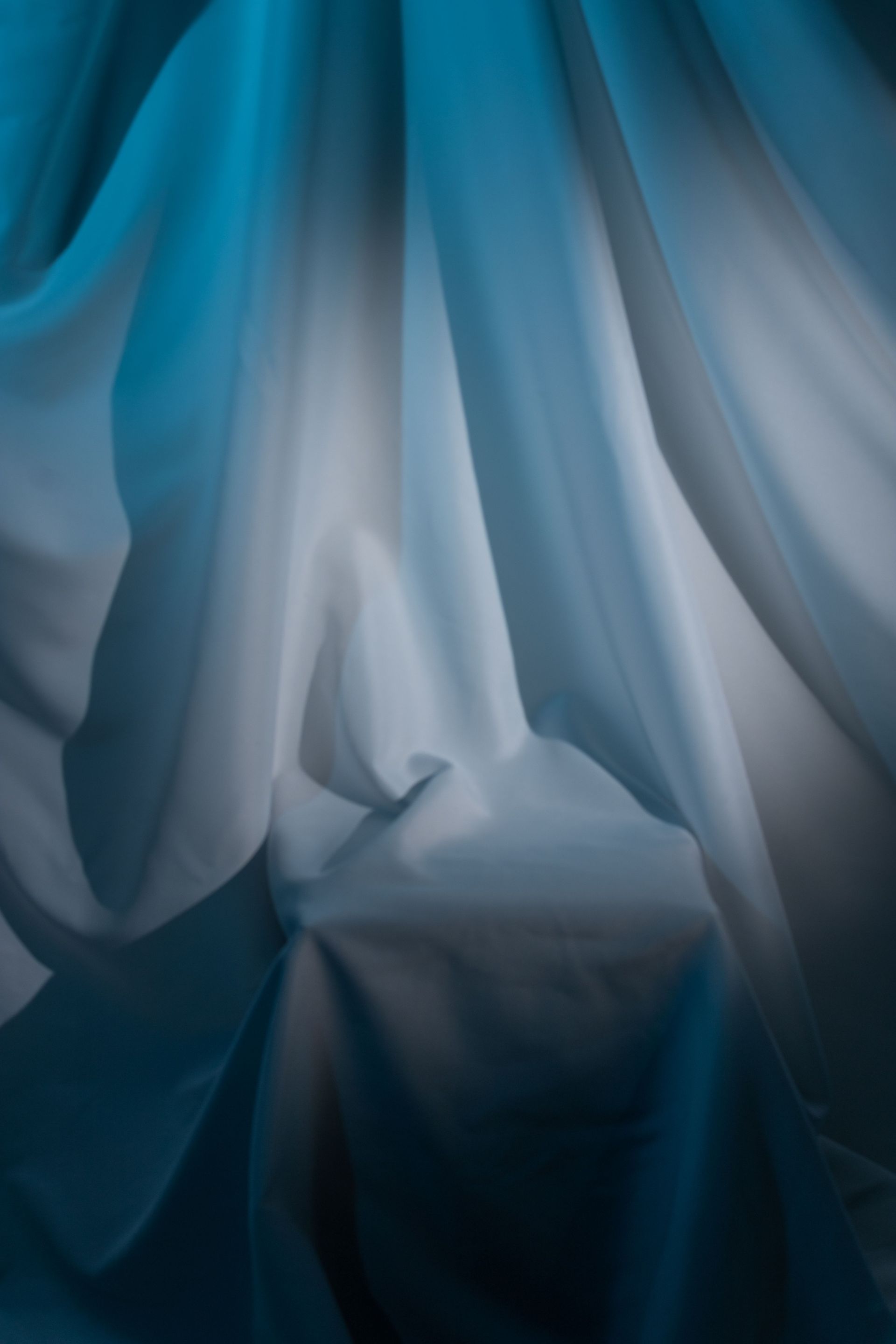 Abstract blue and white draped fabric with soft folds and shadows