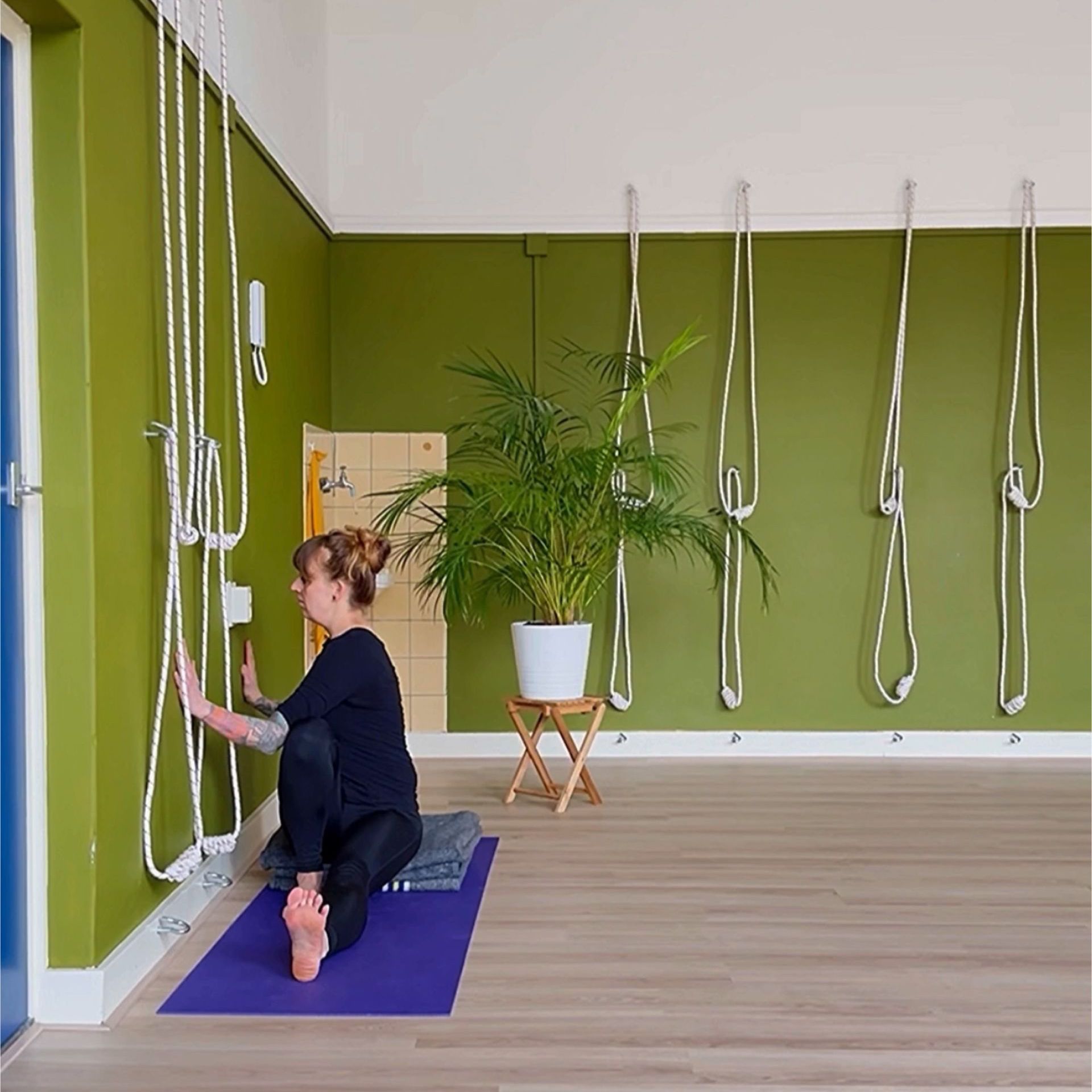 Zittende dichte twist houding met de handen tegen de muur.
