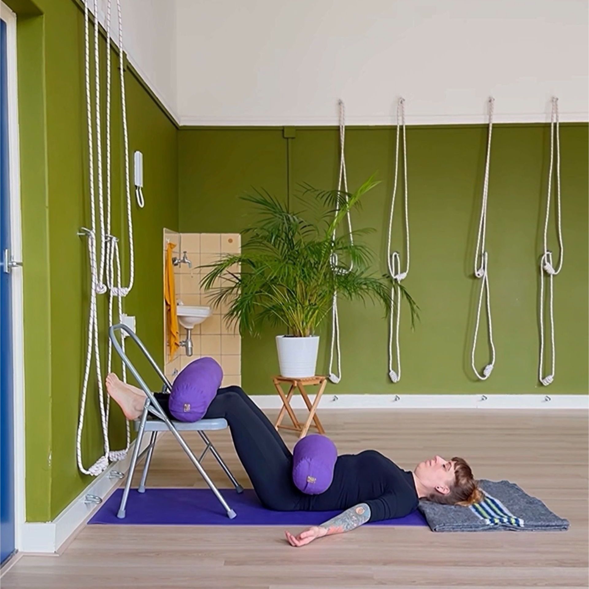 Savasana met een yogastoel en bolsters voor verlichting van de onderrug.