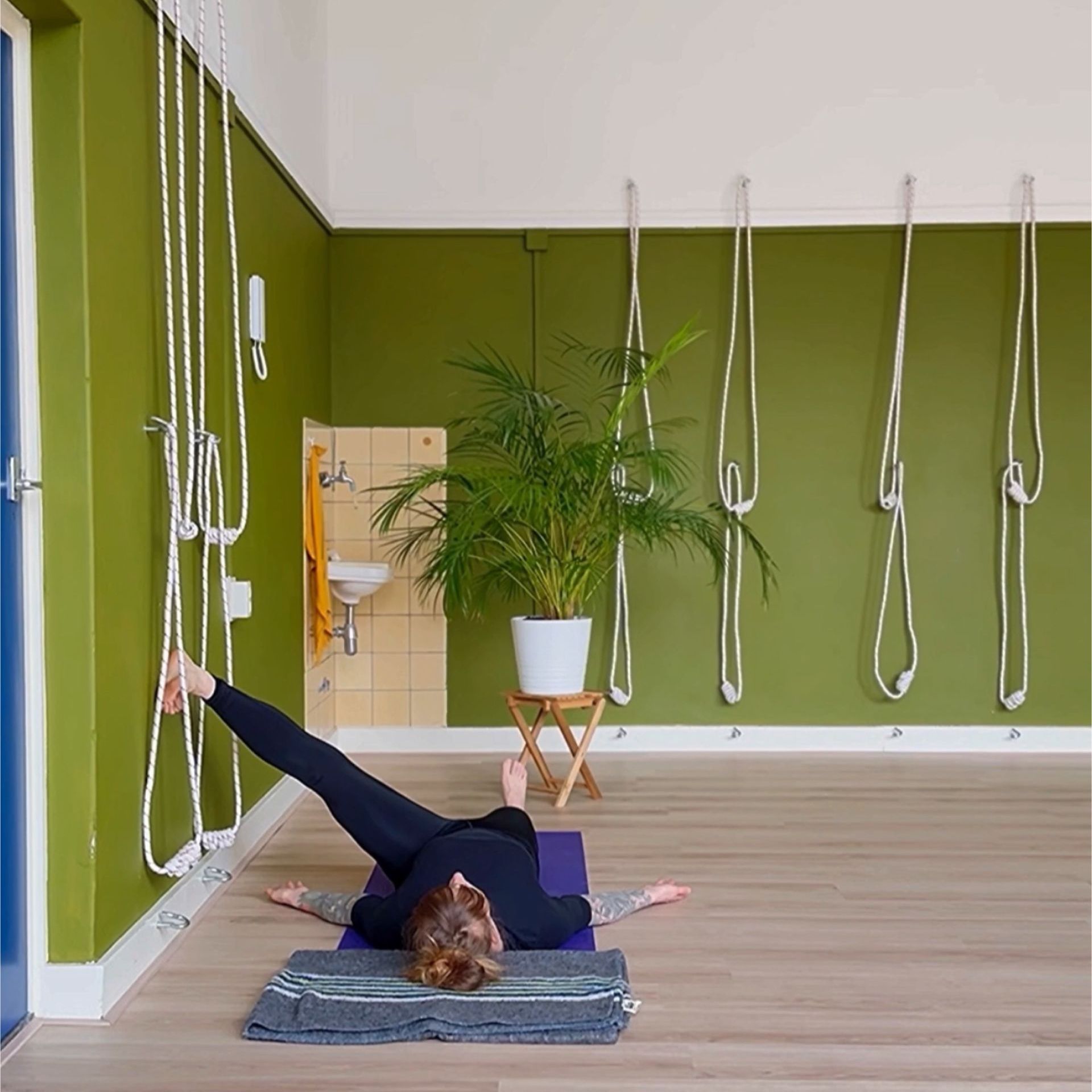 Reclined hand-to-big-toe-pose. Met getilde voet zijwaarts tegen de muur.