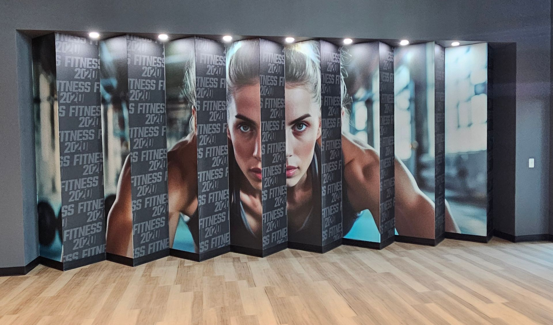 Accordion-style mural with a large face and motivational text on a wood floor in a modern lobby