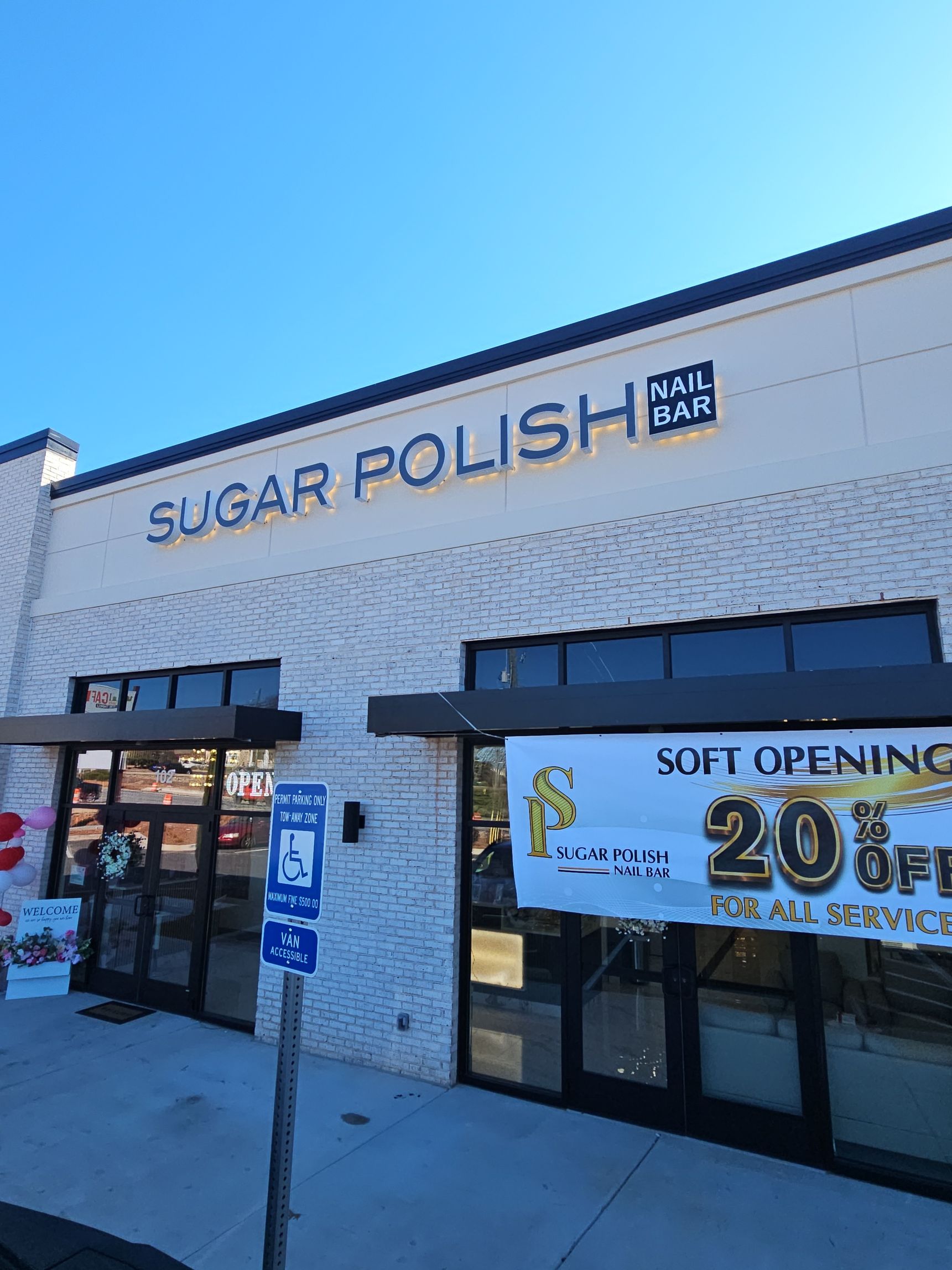 Sugar Polish storefront with white brick facade, blue awning, and bright sale sign in the window