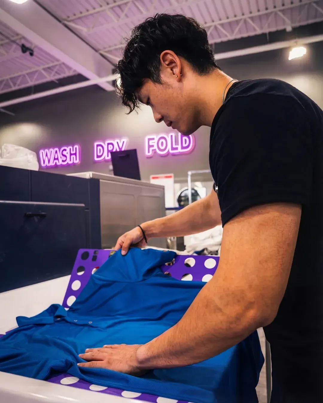 A Hyperloop team member folding clothes in the wash and fold facility