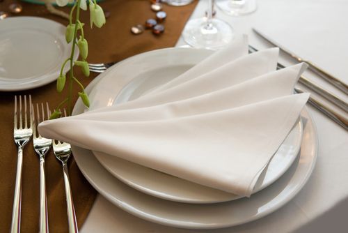 A formal table setting with white plates, folded white napkin, and silverware.
