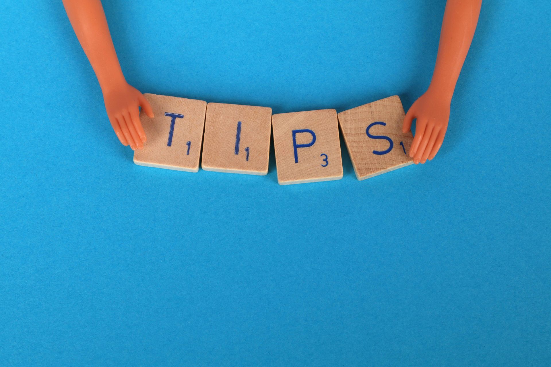 Doll hands arranging Scrabble tiles spelling