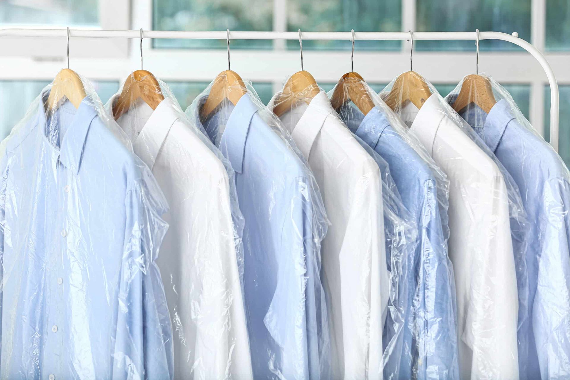 Shirts on hangers in dry cleaning bags.
