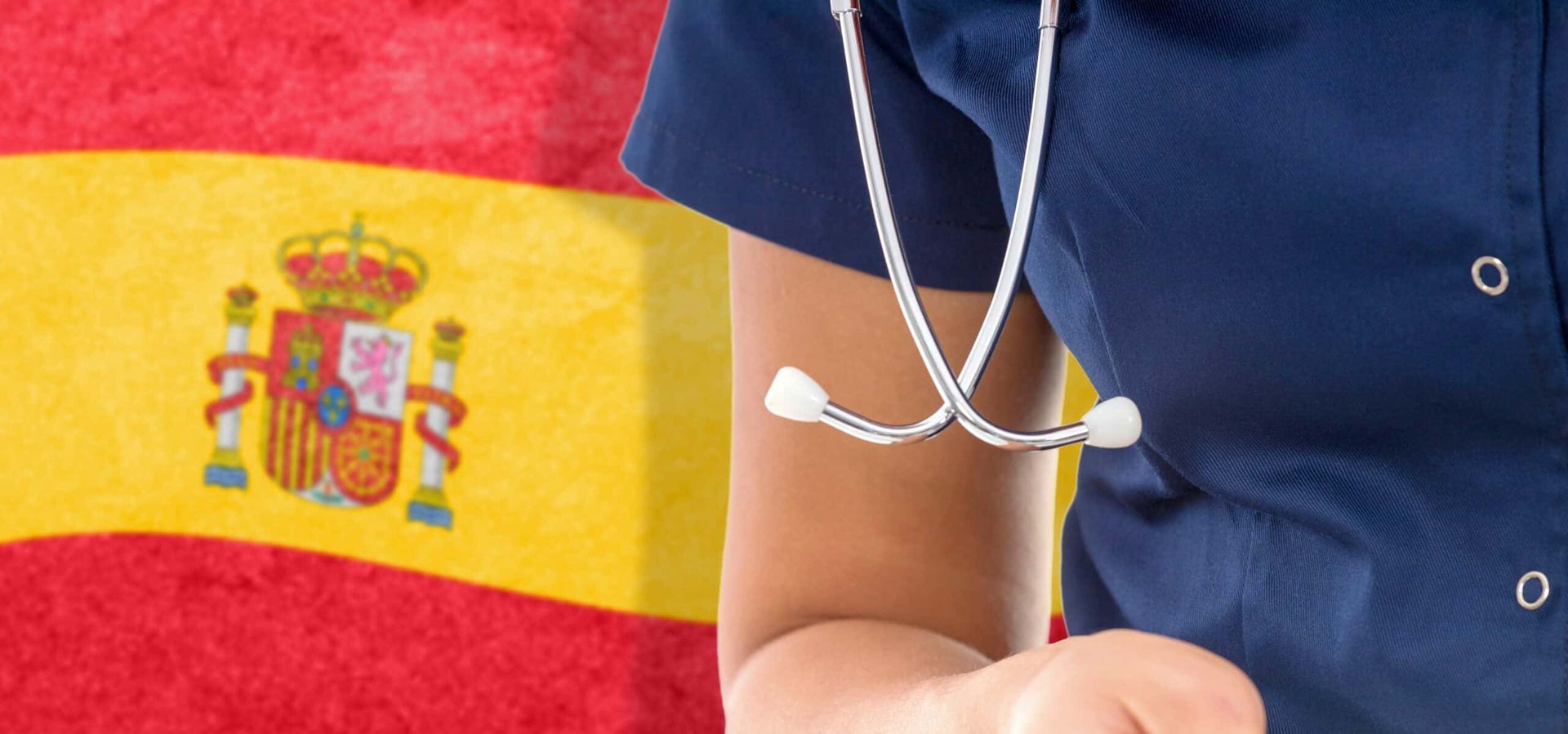 Una enfermera con un estetoscopio alrededor del cuello sostiene una pastilla frente a una bandera española.