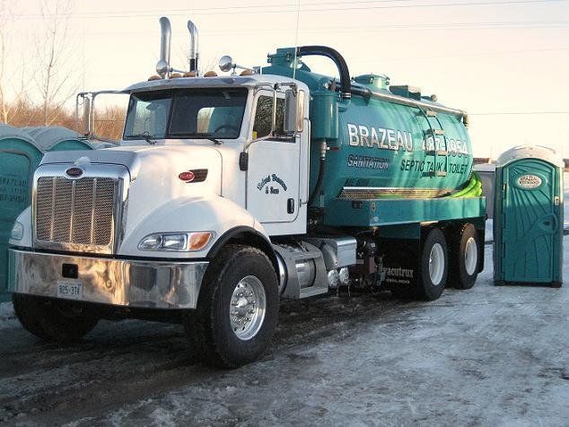 A septic tank and toilet truck is parked on the side of the road.