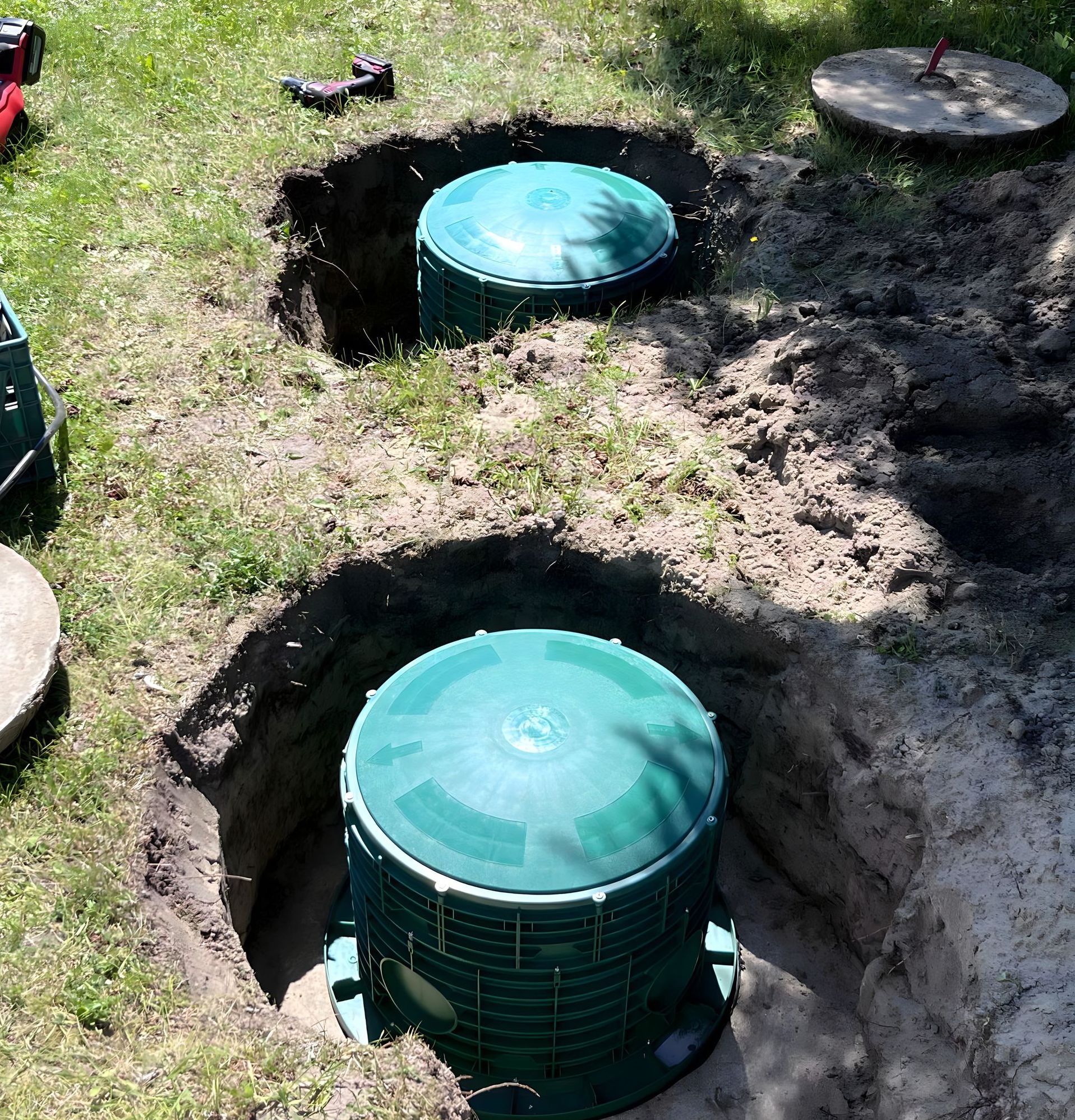 Two green containers are sitting in a hole in the ground Brazeau Sanitation