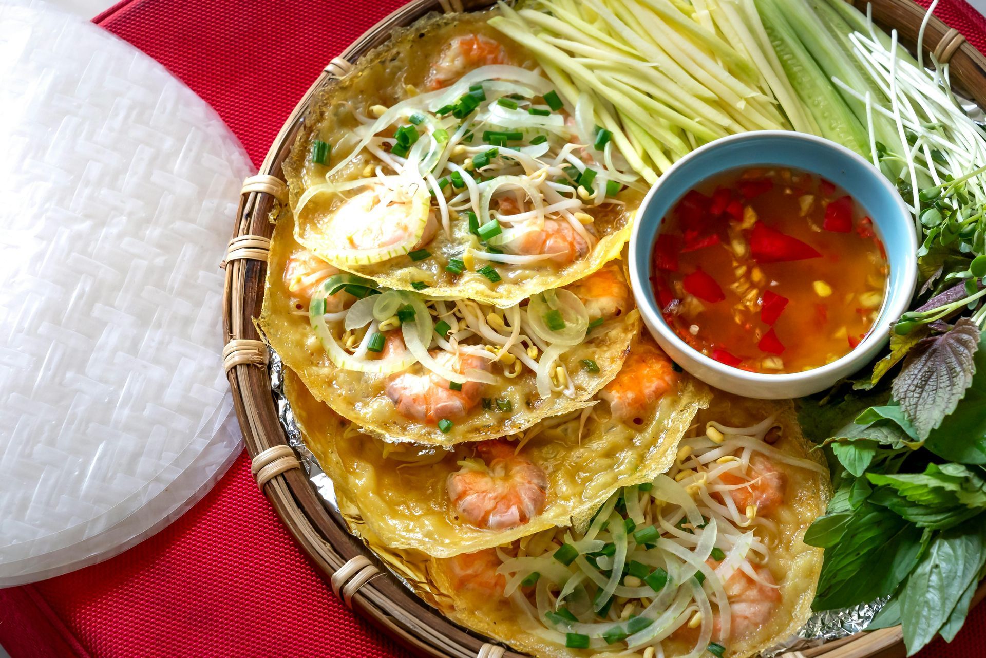 A plate of food with a bowl of dipping sauce and vegetables on a table.