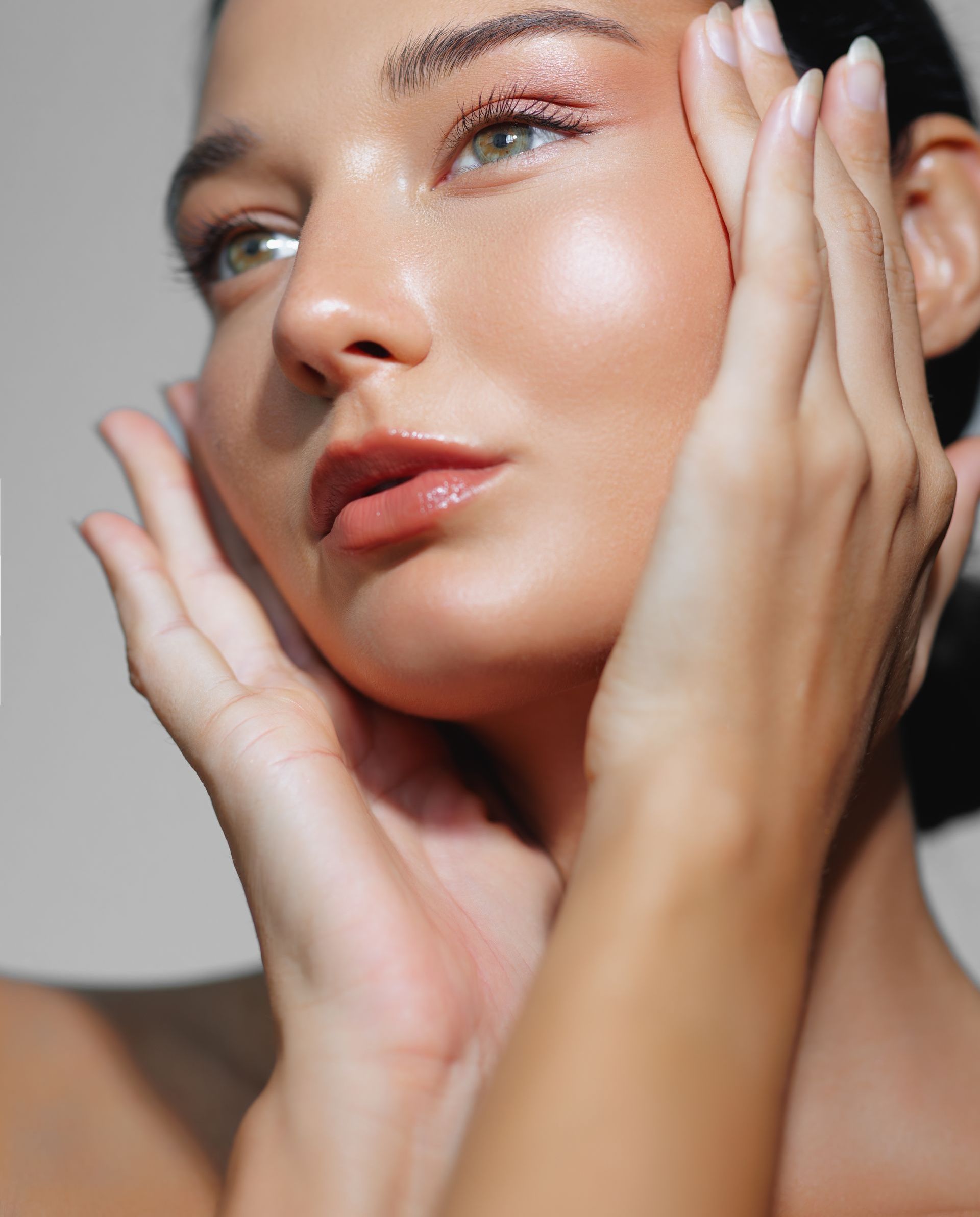 A close up of a woman 's face with her hands on it.
