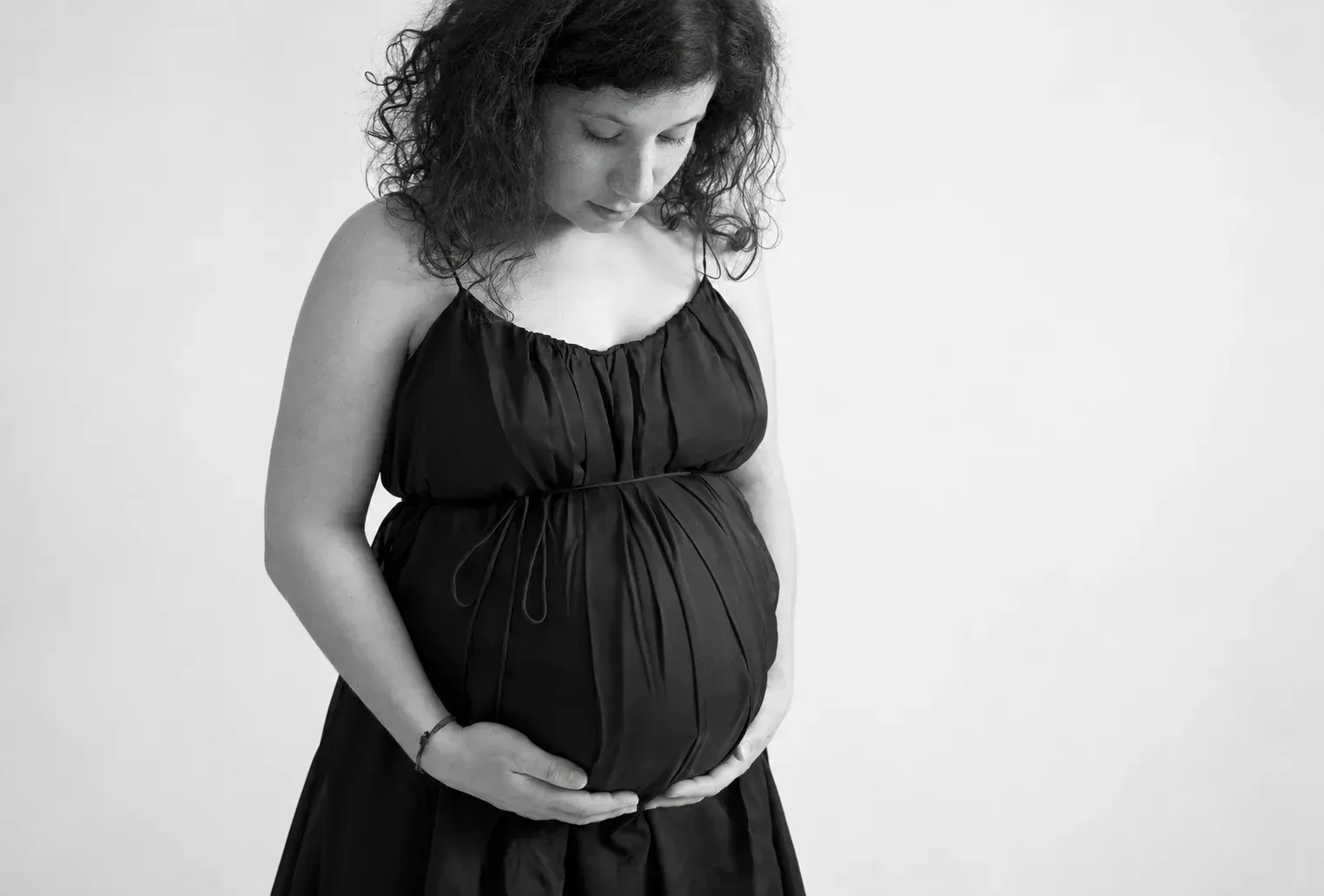 Natürliches Babybauchporträt in Schwarz-Weiß Schwangere Frau hält ihren Babybauch in einem Schwarz-Weiß-Porträt