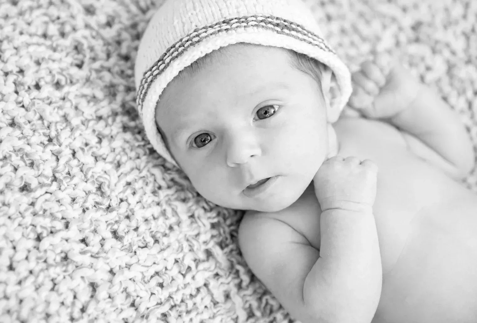 Natürliches Babyporträt in Schwarz-Weiß Waches Baby mit Mütze in einem natürlichen Schwarz-Weiß-Porträt