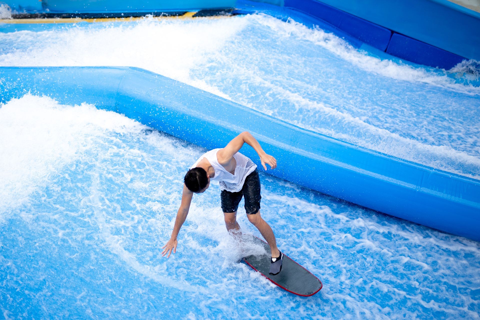 A man is riding a wave on a surfboard in a water park.