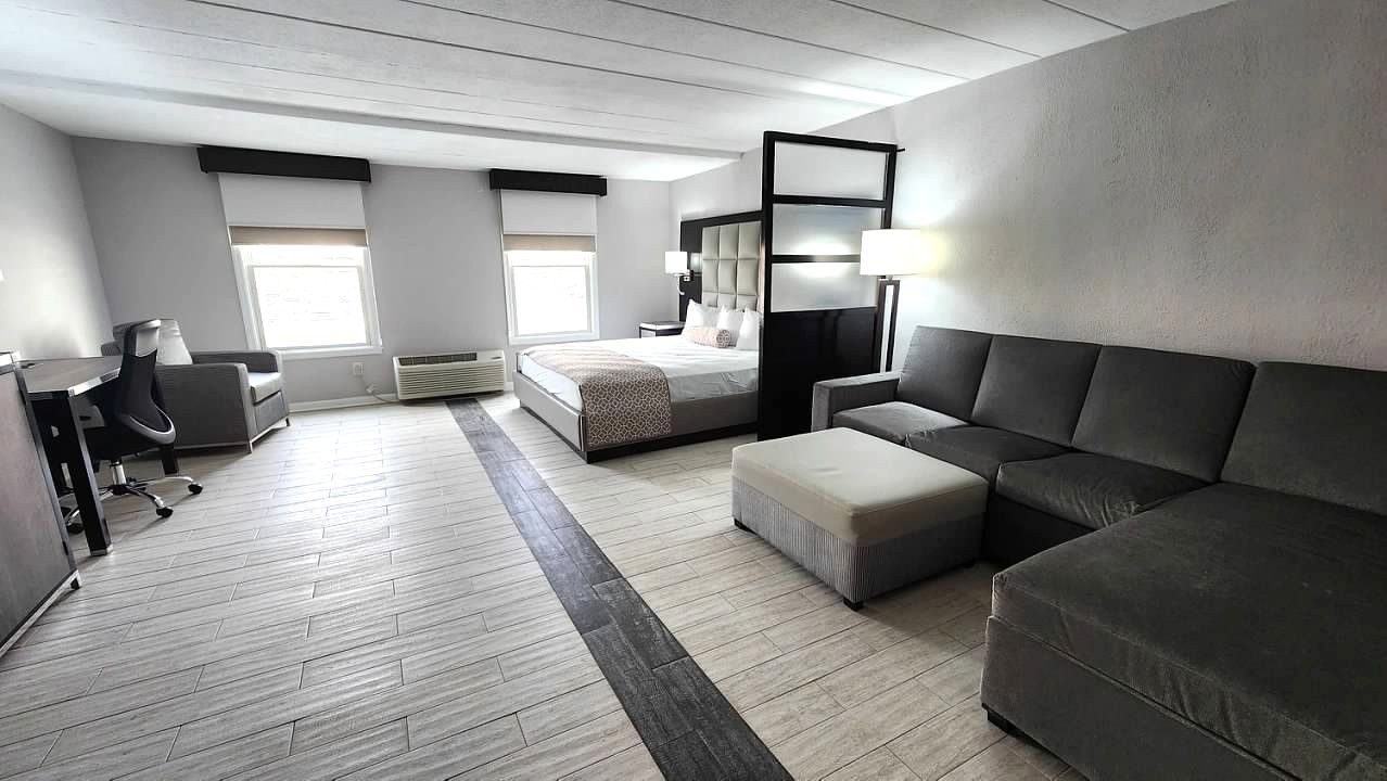 A hotel room with a couch , ottoman , and bed.